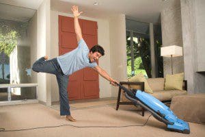 A man is doing a trick with a vacuum cleaner.