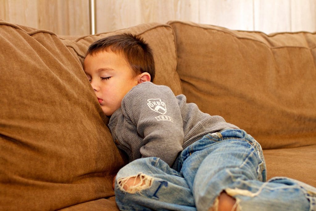 A young boy is sleeping on the couch