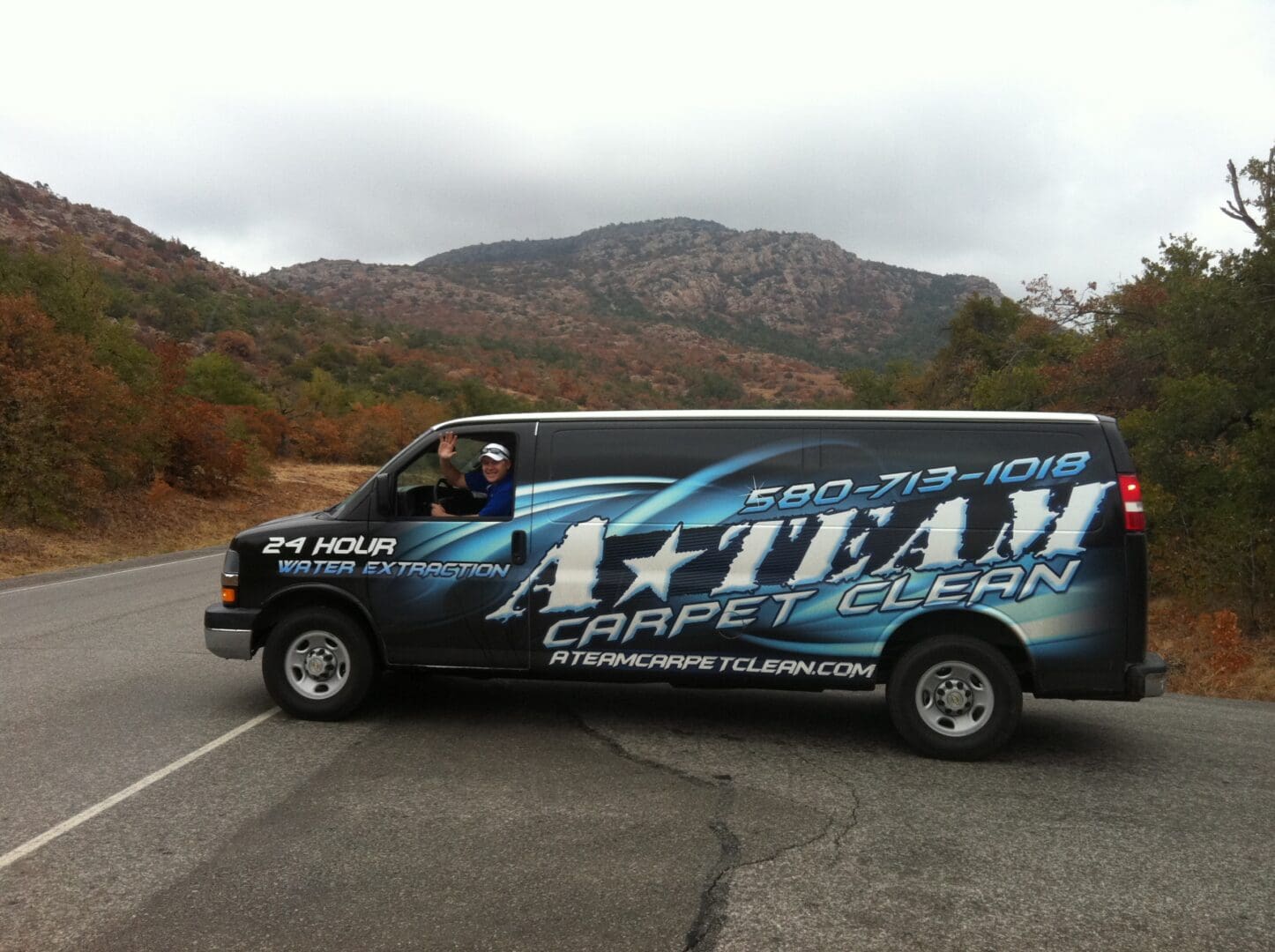 A van with the company logo on it is driving down the road.