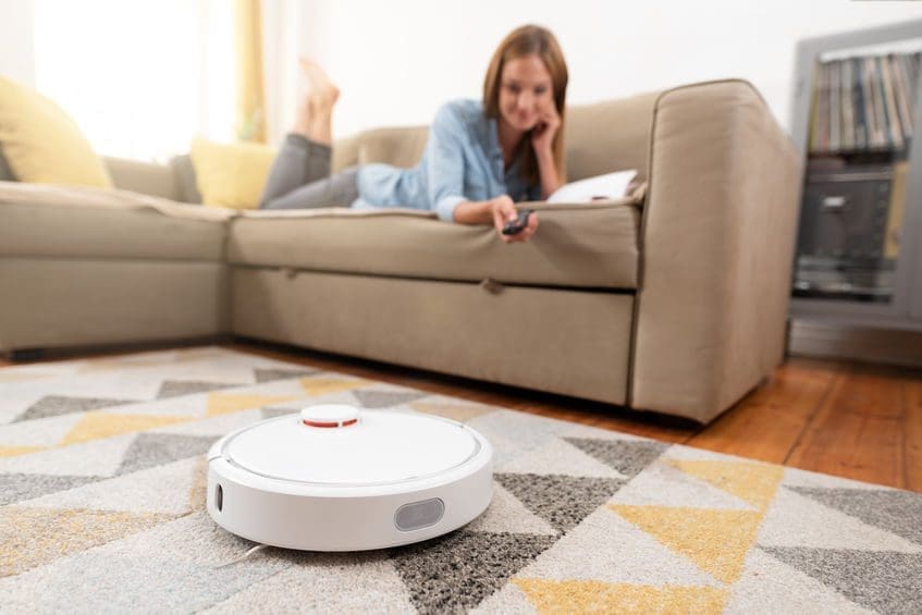 Woman relaxing while robot vacuum cleans floor.