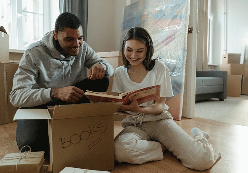 A man and woman sitting on the floor reading books.