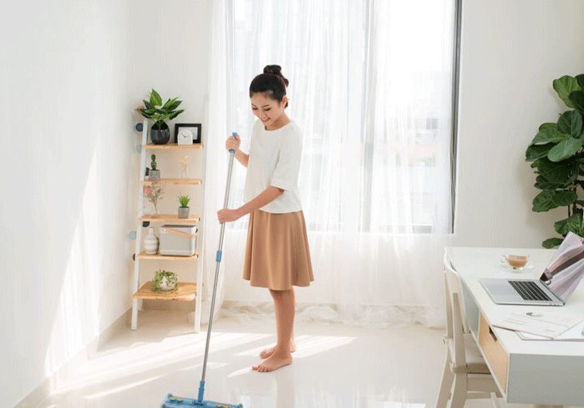 A woman is mopping the floor in her home.