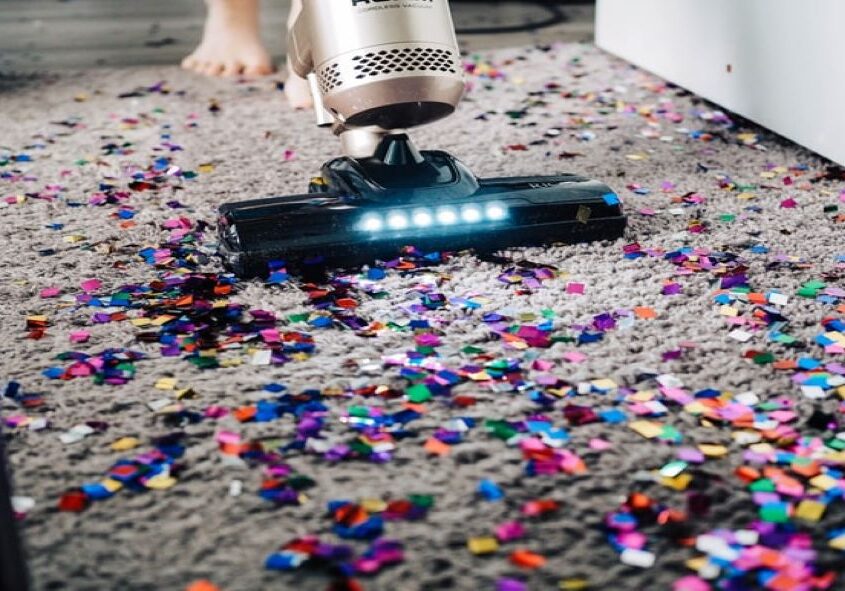 A person using a vacuum to clean up confetti.