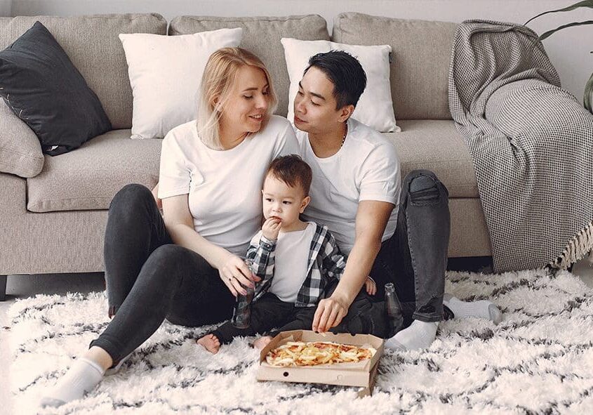 A man, woman and child sitting on the floor.