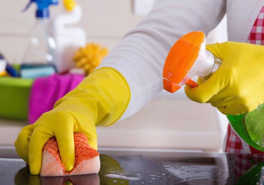 A person wearing yellow gloves and cleaning the counter.